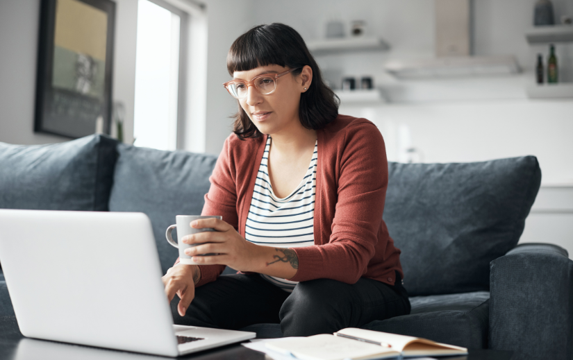  Woman researching dropshipping niche markets on a laptop while holding a coffee mug in a home office.